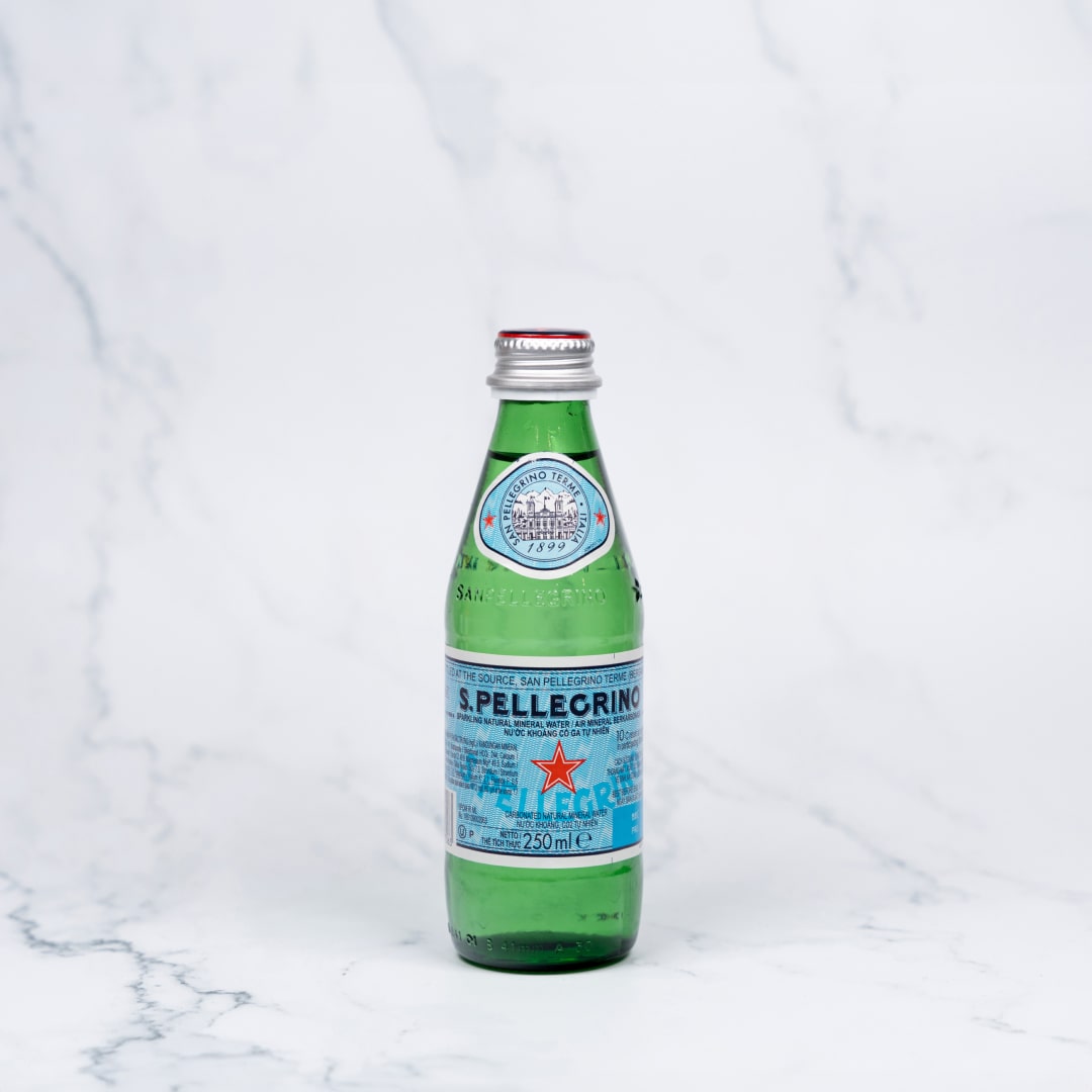 A 250ml glass bottle of San Pellegrino sparkling mineral water on a marble background.